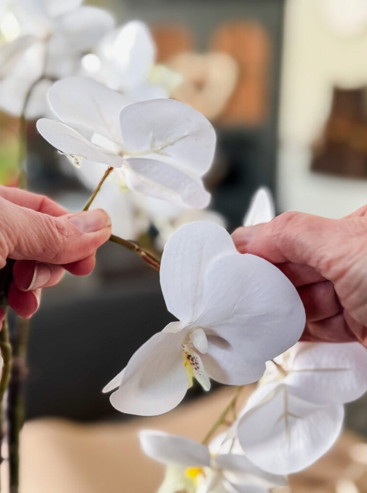 hand bending a faux orchid flower branch