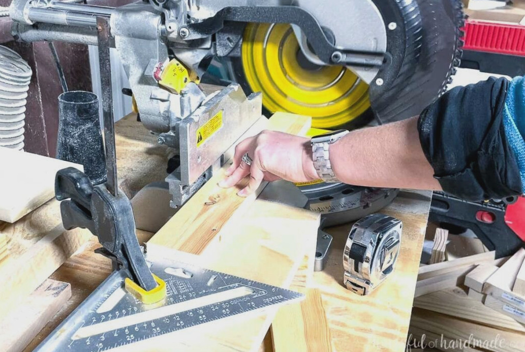 A 1x3 board being cut on a miter saw with a speed square secured to the table as a guide.