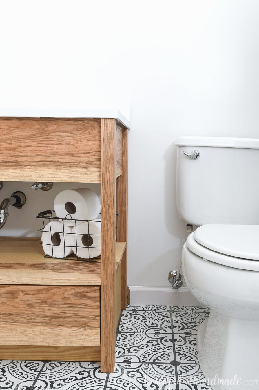 Contemporary bathroom vanity with an open shelf and lower drawers in a bathroom with a black & white patterned tile floor.
