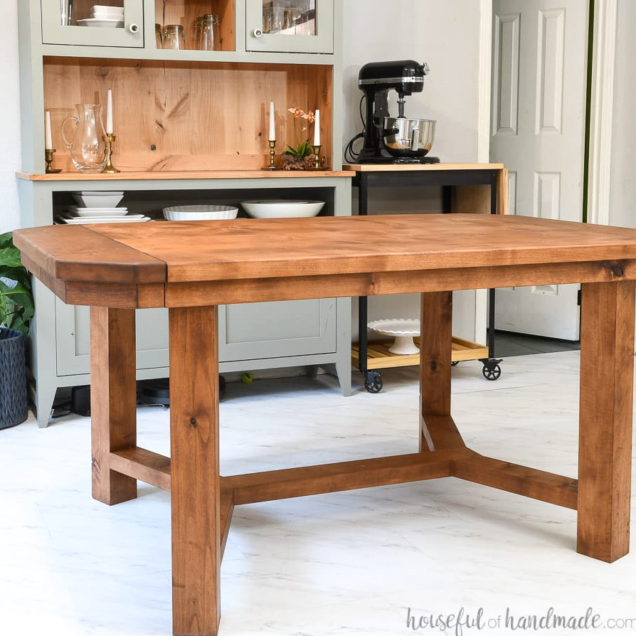 DIY trestle-style dining table with 2 leaves positioned in the dining room before a hutch.