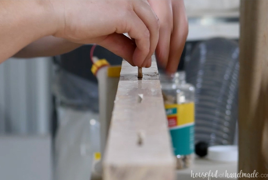 Placing biscuits into the slots along a board edge coated with wood glue.