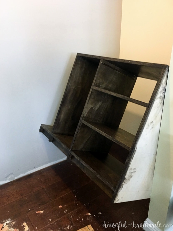 Plywood closet shelves being shimmied into the closet. 