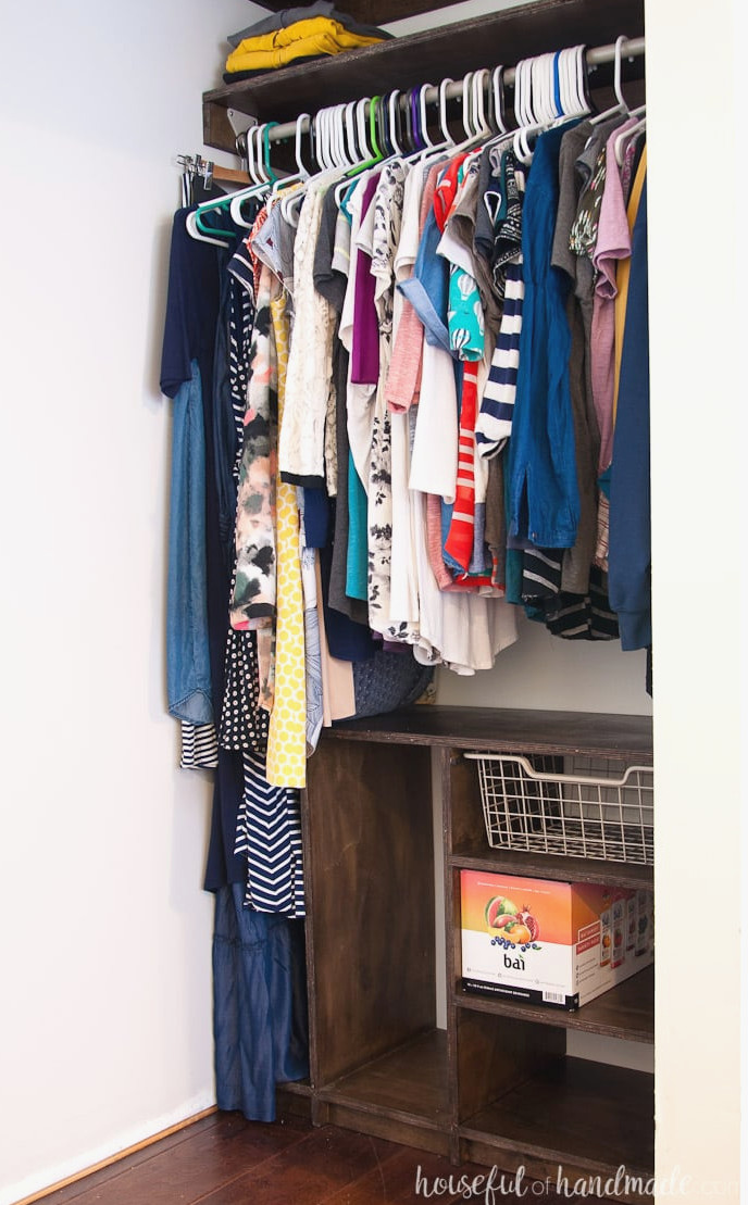 Compact closet with DIY plywood shelves above and a custom organizer below, including space for folded clothing.