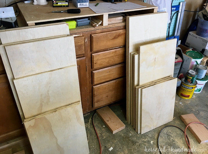 Cut plywood components piled beside the workbench in a garage. 