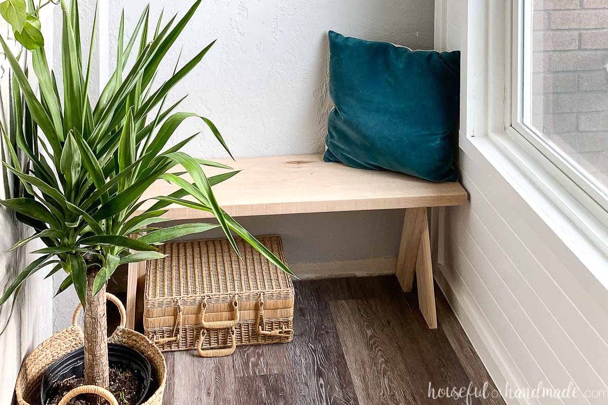 Wide view of the bench in the entryway surrounded by a plant and decorative accessories. 