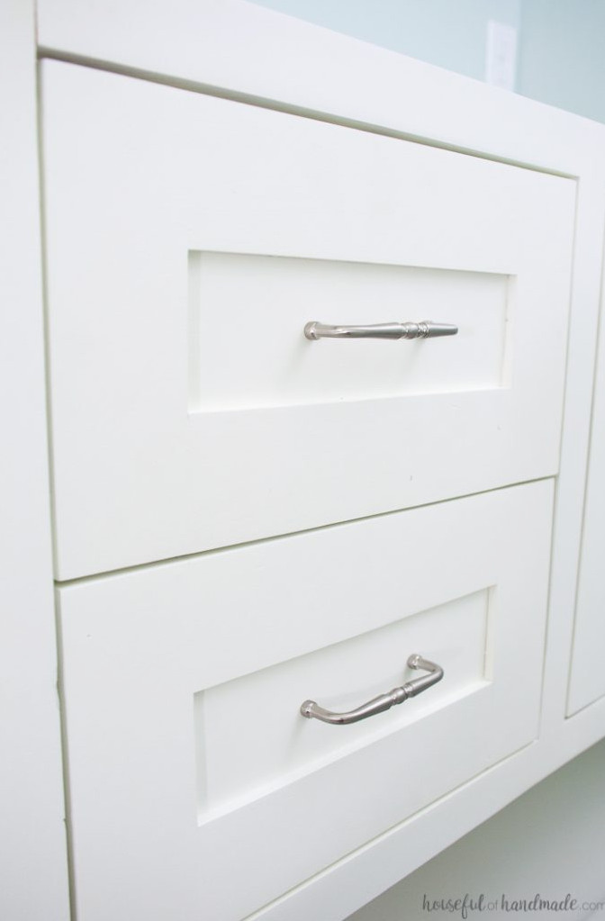 Inset shaker doors on a bathroom vanity featuring silver pulls on the center panels. 