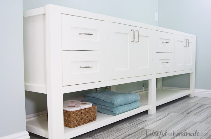 White furniture-style bathroom vanity featuring an open lower shelf. 