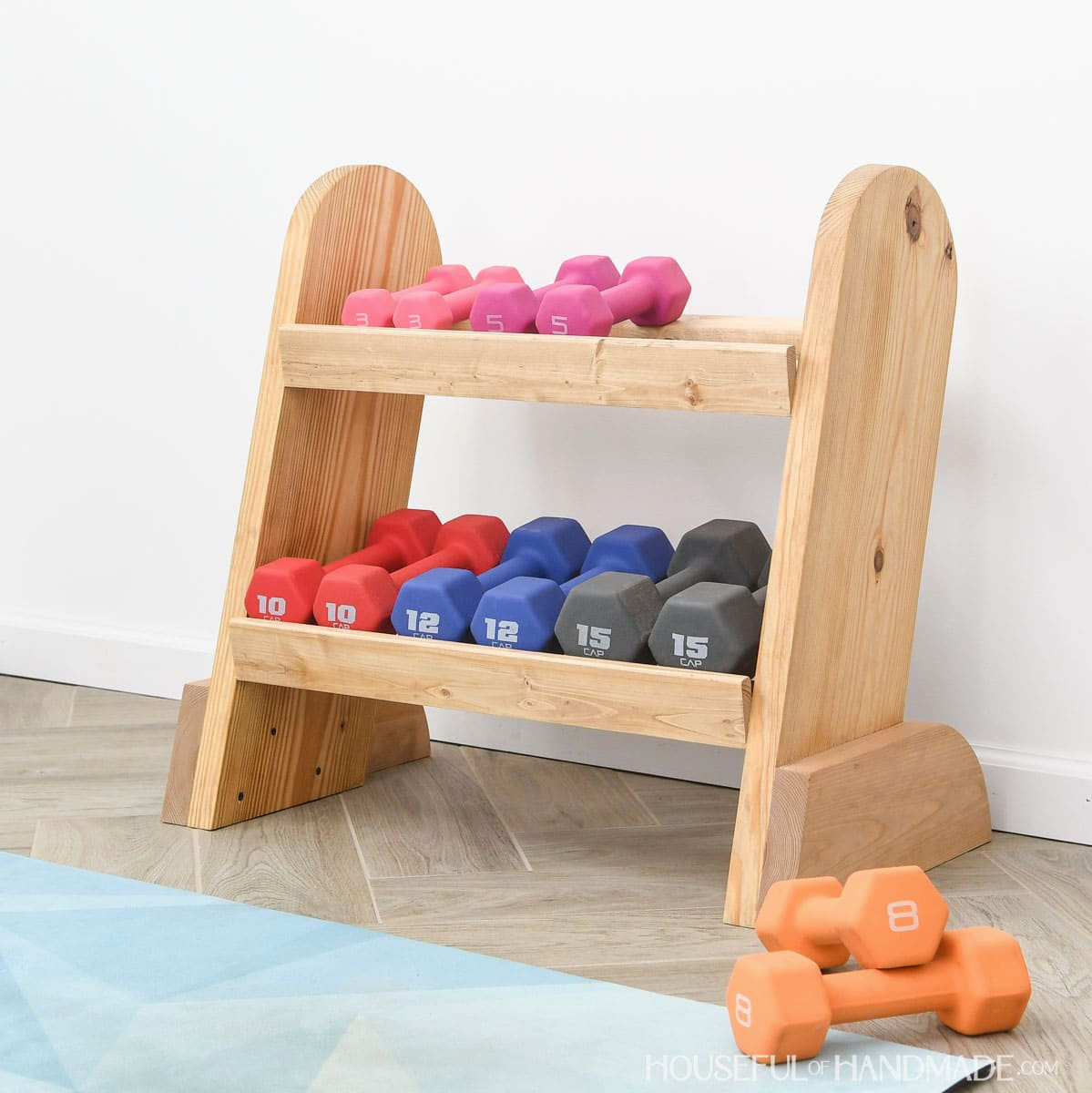Compact DIY wooden weight rack holding colorful dumbbells.