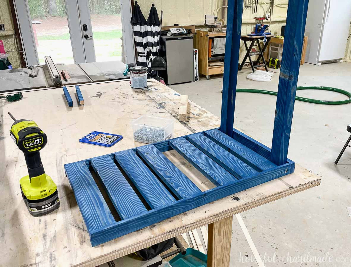 The stained bottom shelf being fastened to the rear 2x2 pieces. 