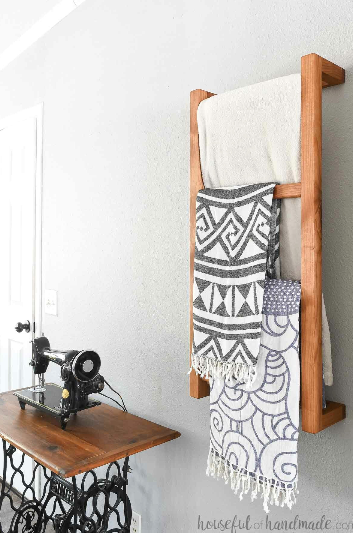 Side perspective of the wall-mounted ladder beside a vintage sewing table covered with blankets. 