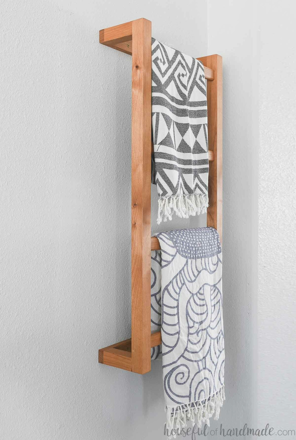 Detailed view of the wooden wall-mounted ladder holding 2 blankets. 