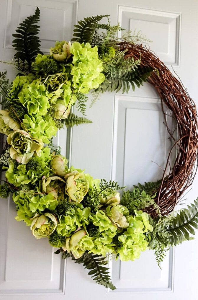 front door with a wreath made with green hydrangeas and peonies