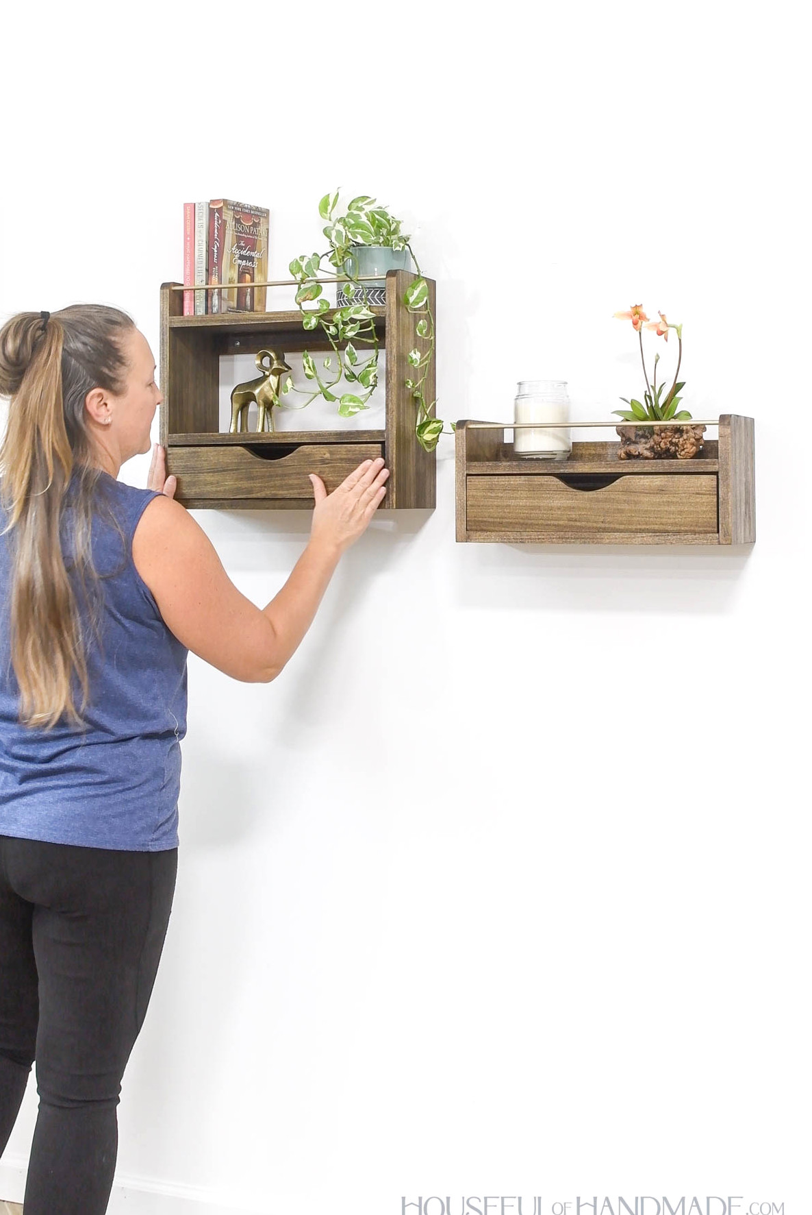 Kati looking at 2 wood wall shelves with a drawer on the bottom.