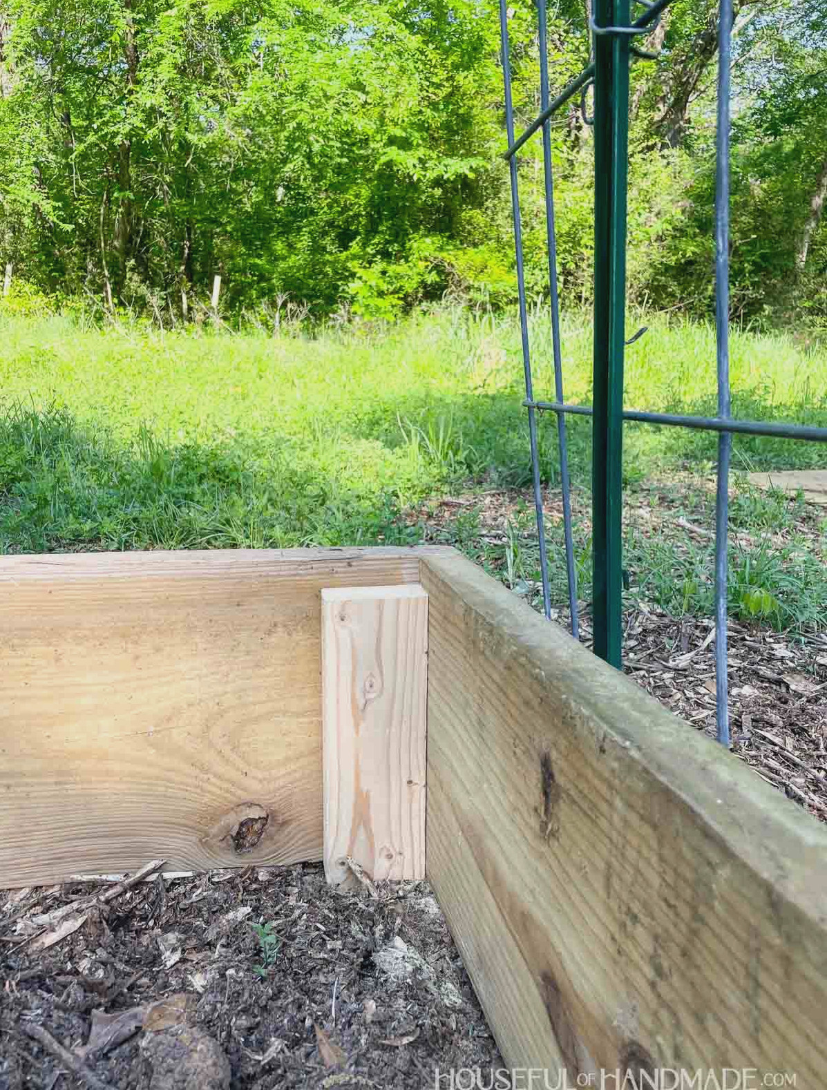 Interior of the wooden garden bed before soil is added, with a support piece visible in the corner. 