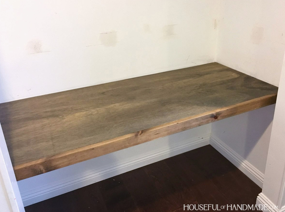 Dark stain wood desk top inside of office closet.