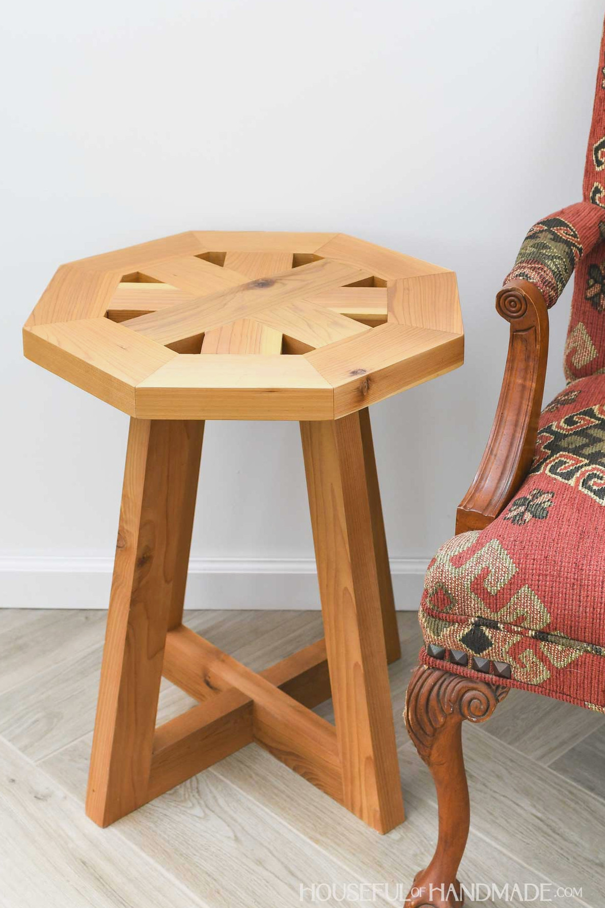 Side table featuring pedestal legs and an octagonal top with tiny openings along the edges. 