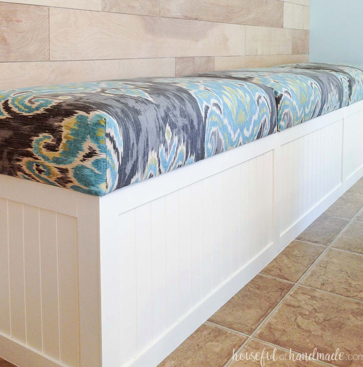 DIY white beadboard-paneled built-in bench with a cushioned top in the dining room.