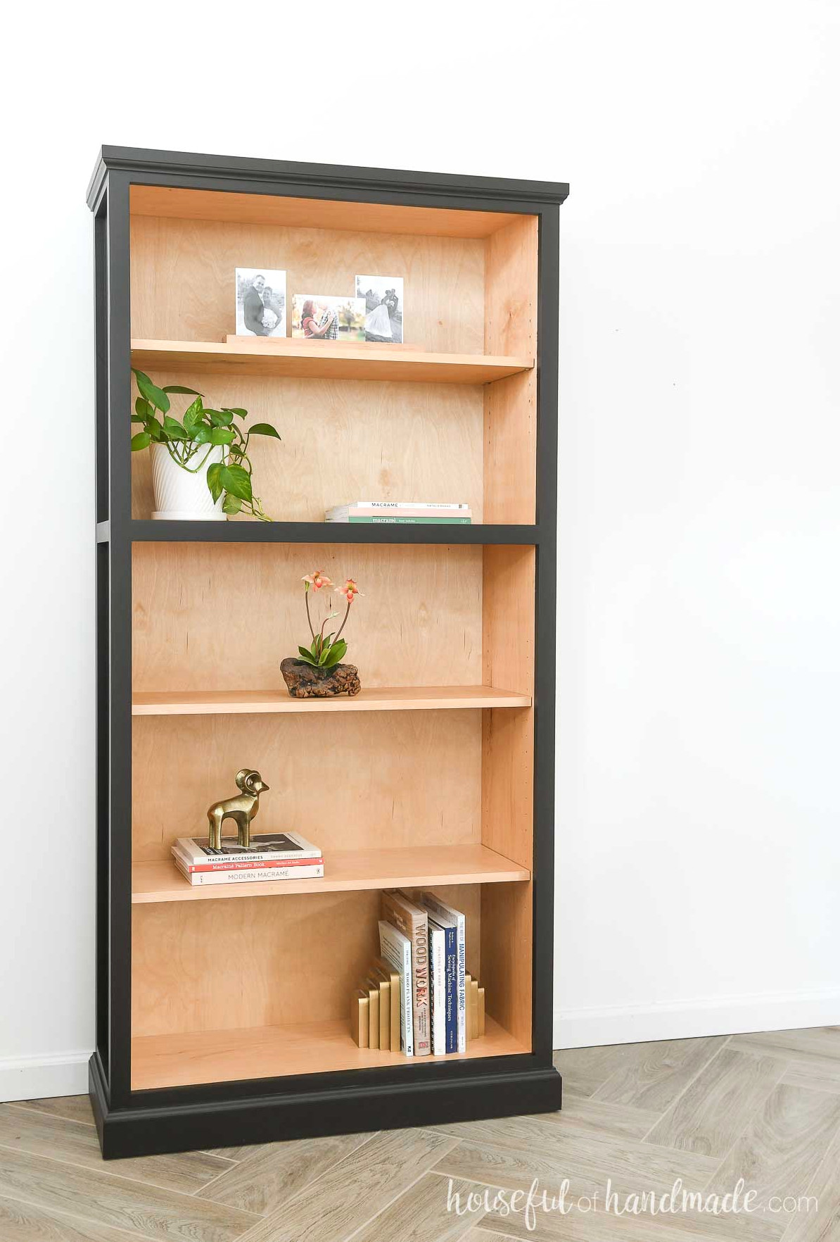 DIY tall bookcase with 5 shelves with natural wood on the inside and black paint on the outside.