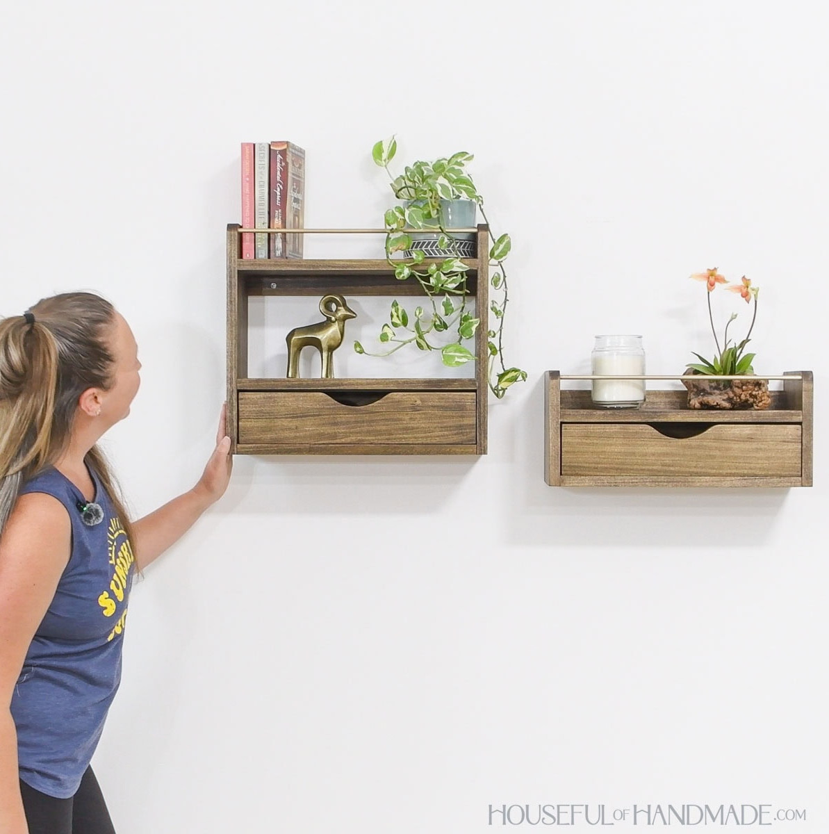 Girl standing next to two floating wall shelves with drawers decorated with books, nicknacks and plants.