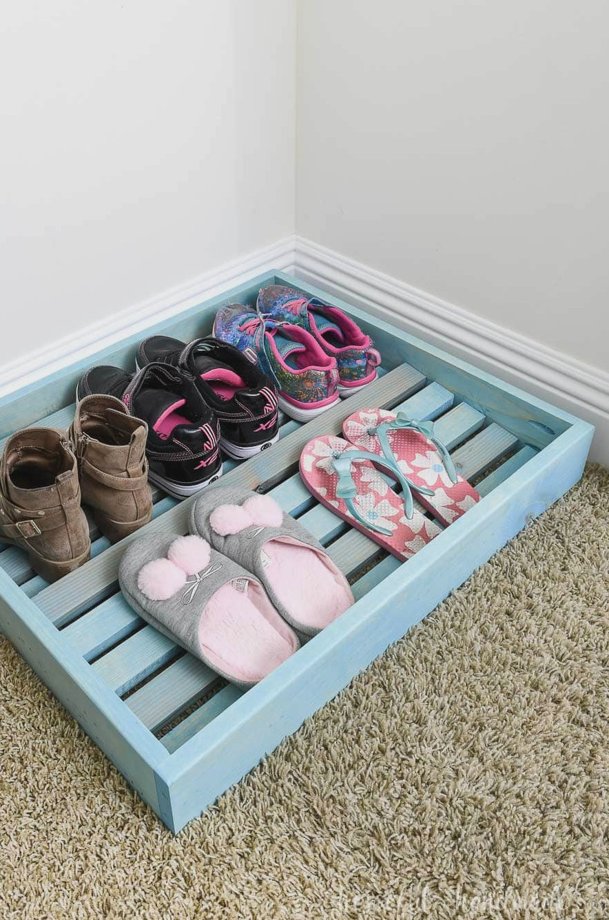 Five pair of kids shoes organized on the shoe storage tray in the closet.
