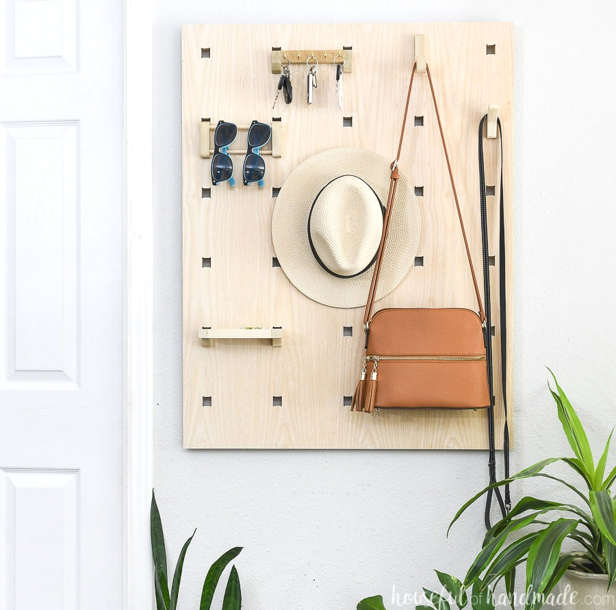 Plywood entryway organizer mounted on the wall beside a door.