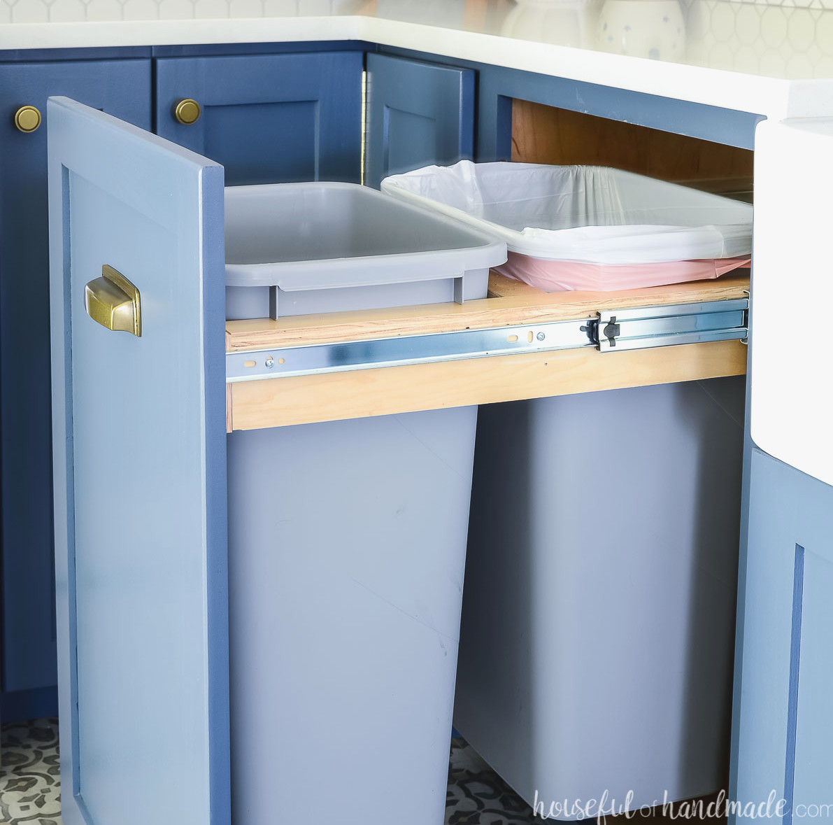 Sliding trash can cabinet opened to show the two spacious garbage bins stored inside.