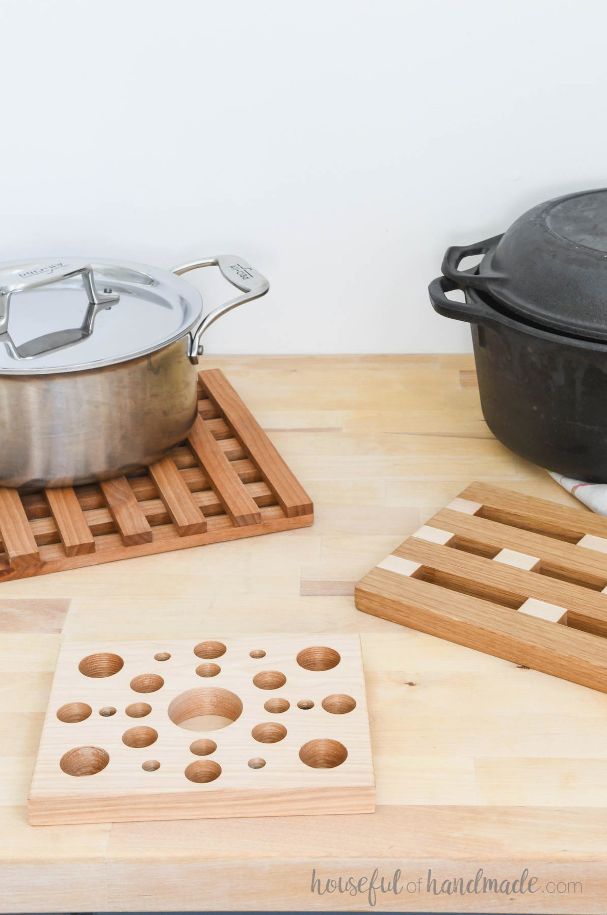 Three varieties of wooden trivets arranged on a butcher-block countertop.