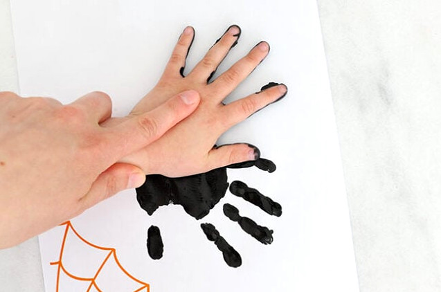 Second spider handprint stamping onto paper
