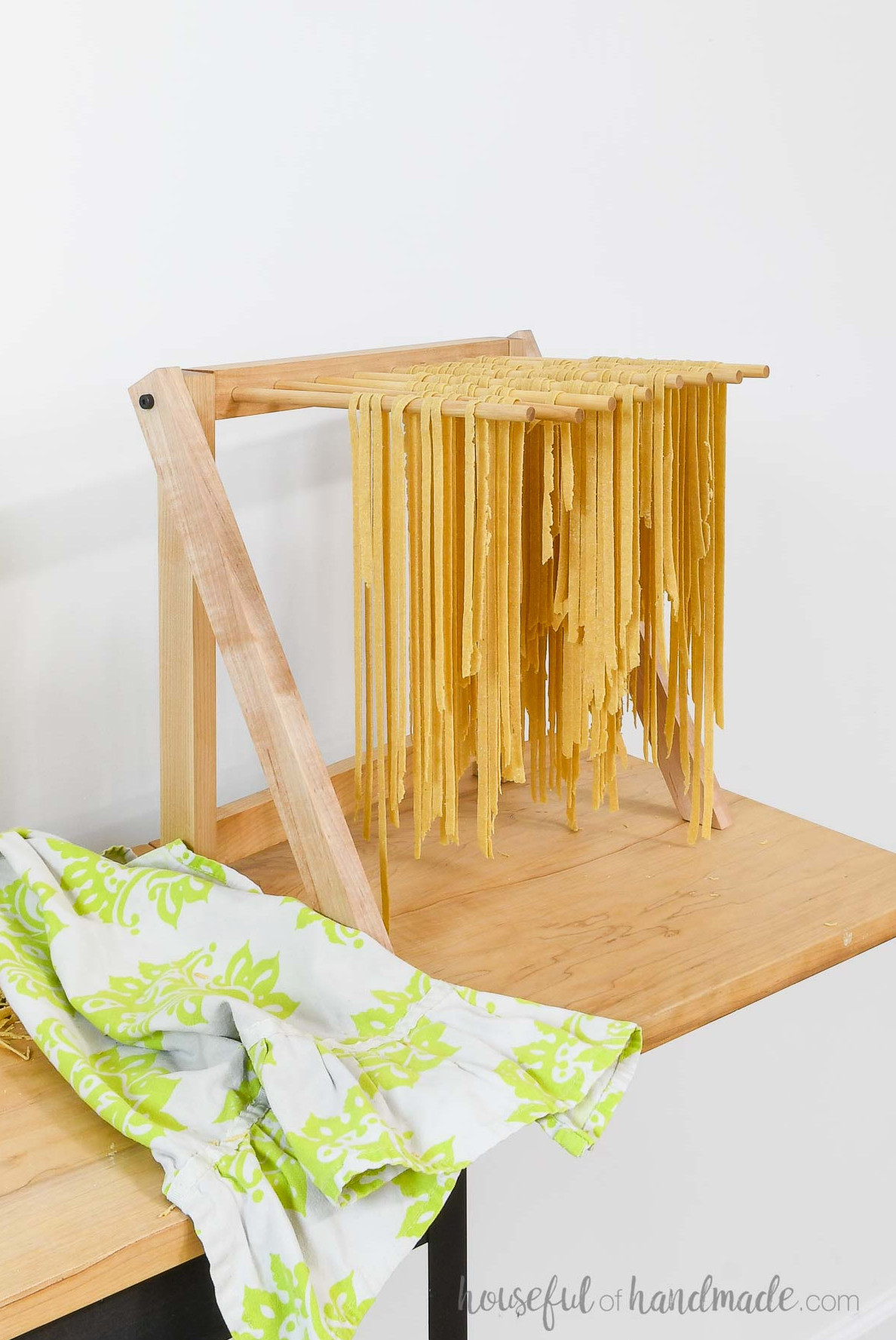 Folding rack with dowels drying homemade pasta on it.