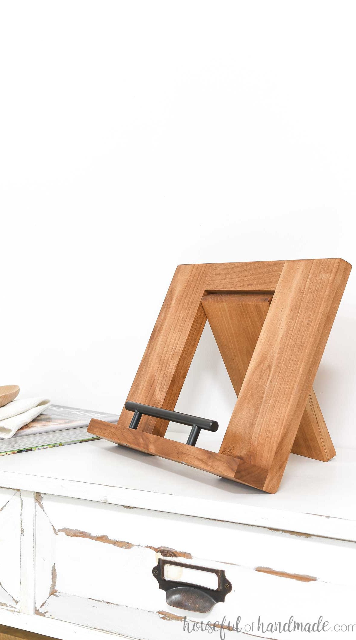 Alder wood folding cookbook holder sitting on a console without a cookbook on it.
