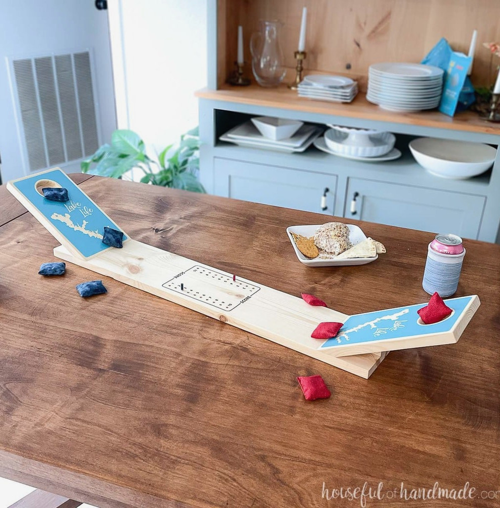 DIY tabletop cornhole board on a table surrounded by red and blue mini bean bags and snacks.