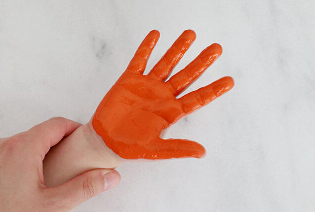 Child's hand covered in orange paint