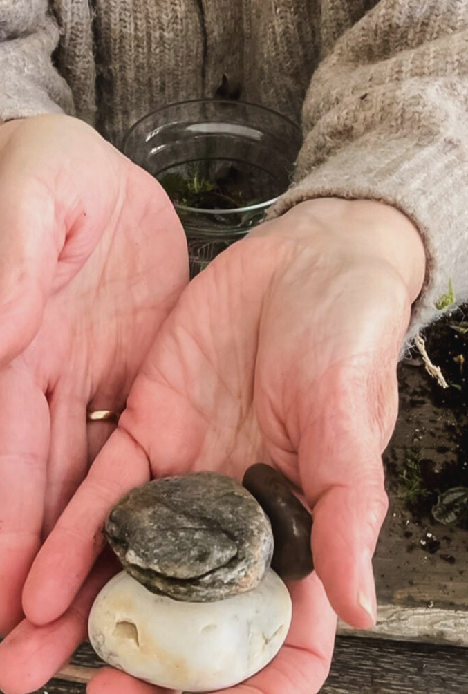 a woman's hand holding 3 beach stones