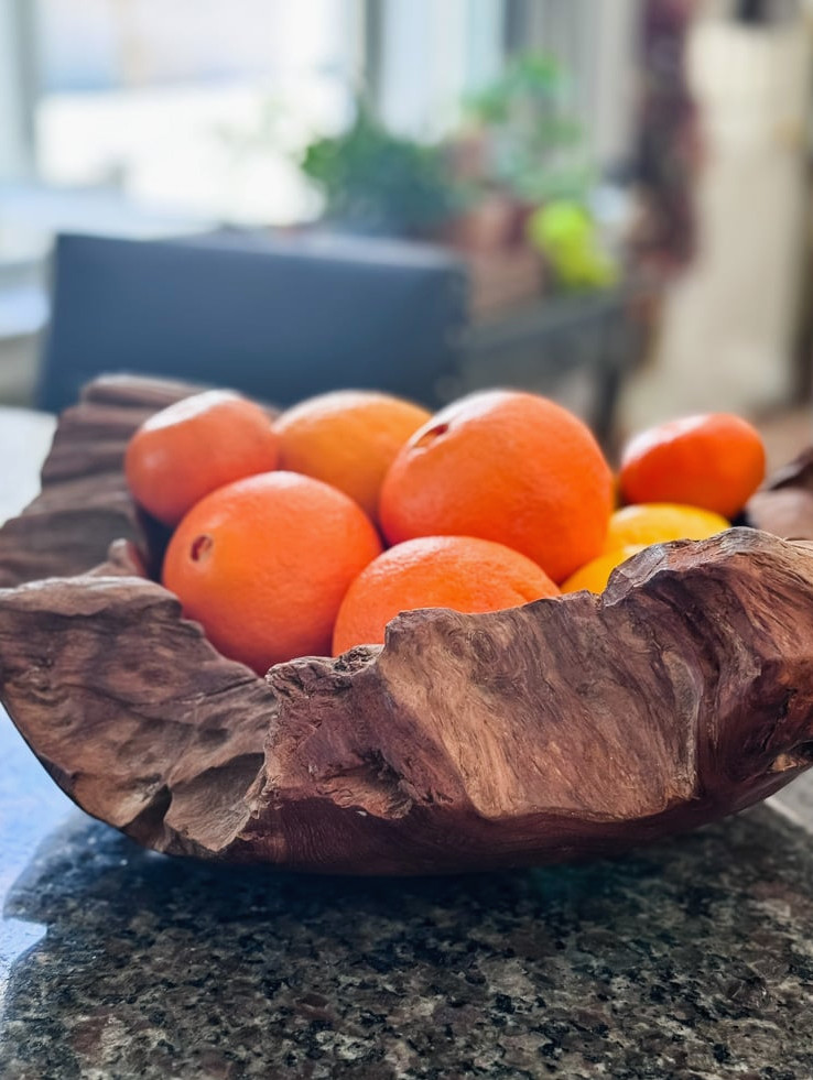 a wood bowl filled with citrus fruit