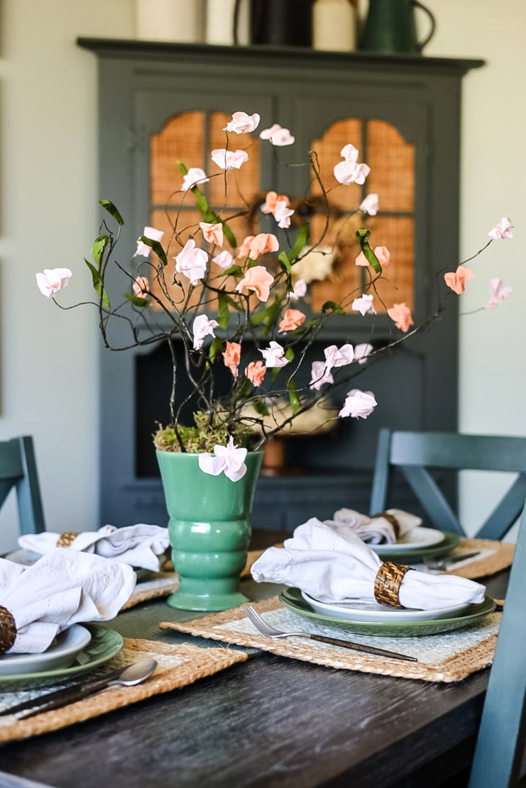 dining table with paper flowers in a green vase