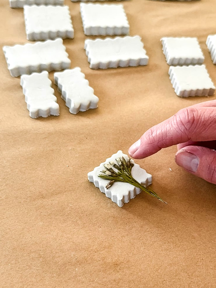 pressing a flower into clay with a finger