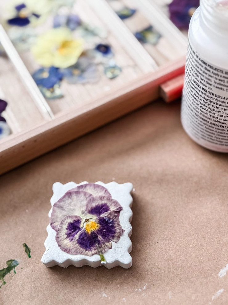 purple pansy being attached to an air-dry clay magnet
