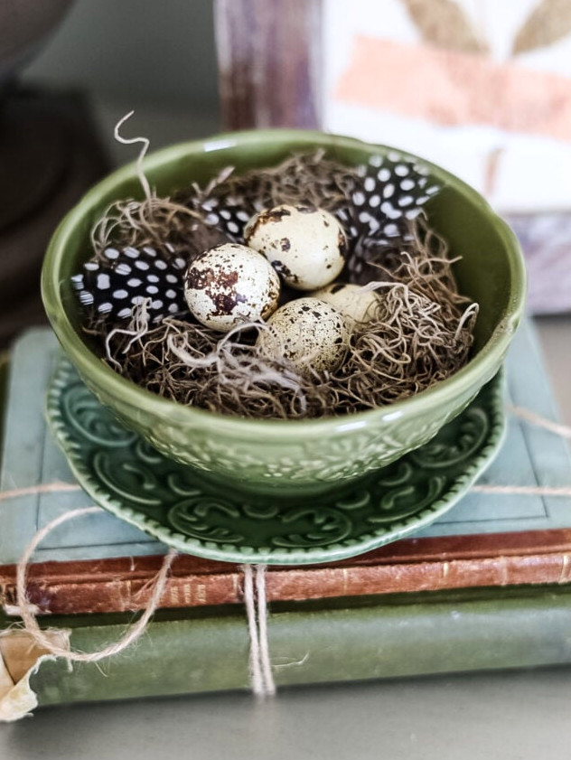 green bowl and saucer with bird eggs on vintage book stack