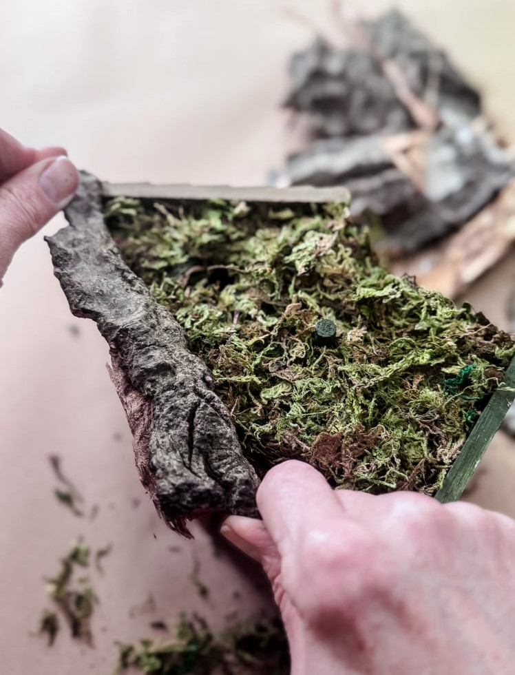 gluing bark onto a birdhouse craft project