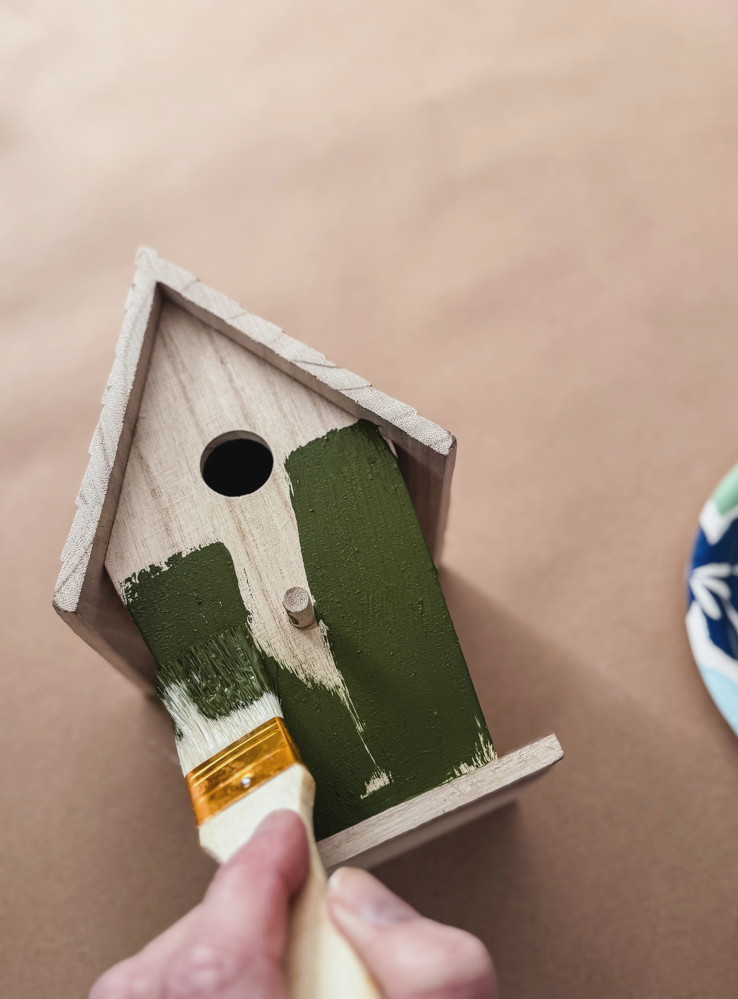 painting a wood birdhouse with green paint