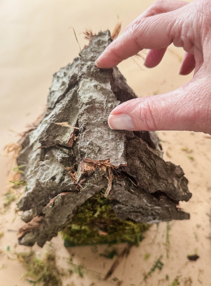 gluing tree bark onto a crafting project of a birdhouse