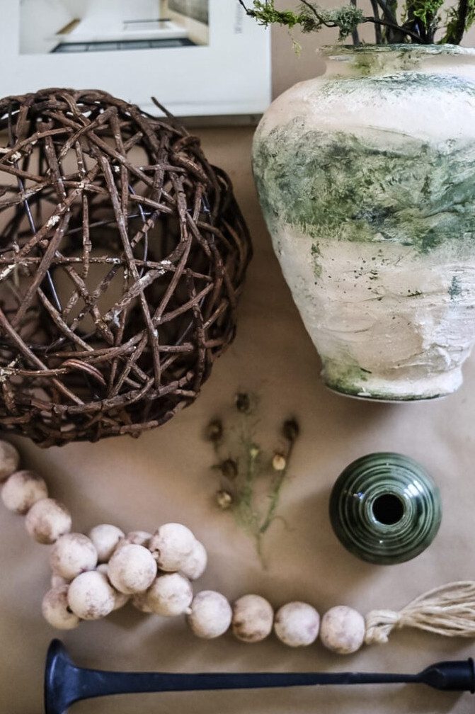 decor to be used to style a mantle including wood beads, vases, grapevine orb, and books