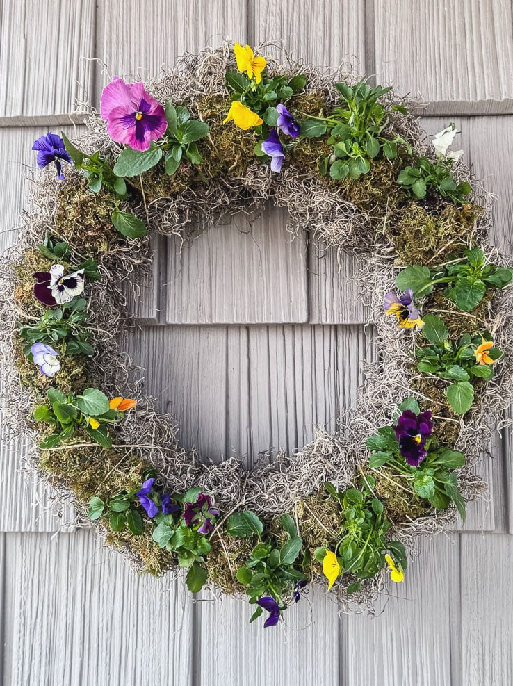living pansy wreath displayed on a home with gray siding
