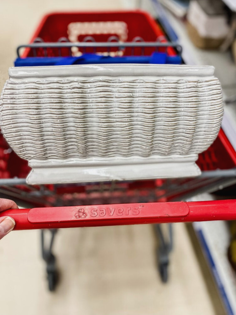a shopping cart with a white ceramic vase in it