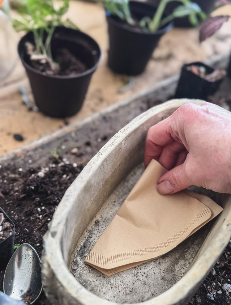 placing a coffee filter at the base of the planter
