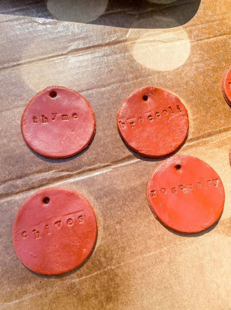 spraying clay plant markers with protective clear coat