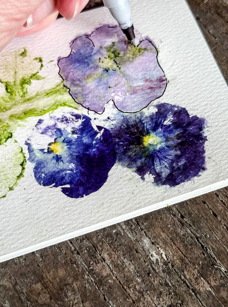 drawing a black marker outline around a pansy print