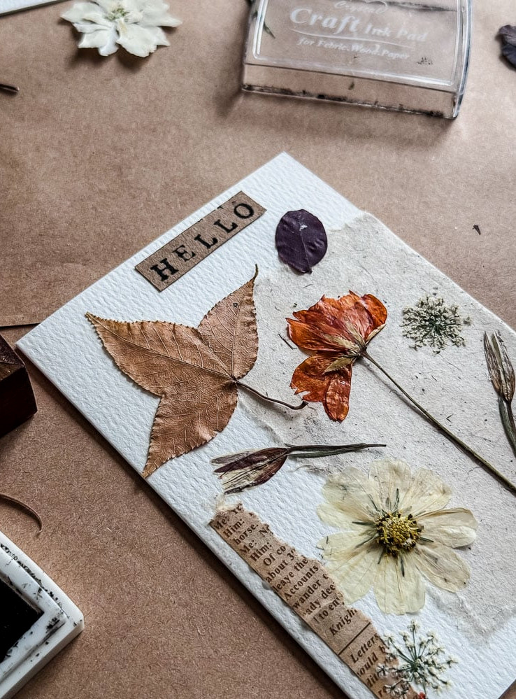 handmade notecard with pressed flowers and 'hello' stamped on it