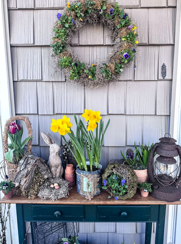 a table outside decorated for spring with flowering daffodils and tulips
