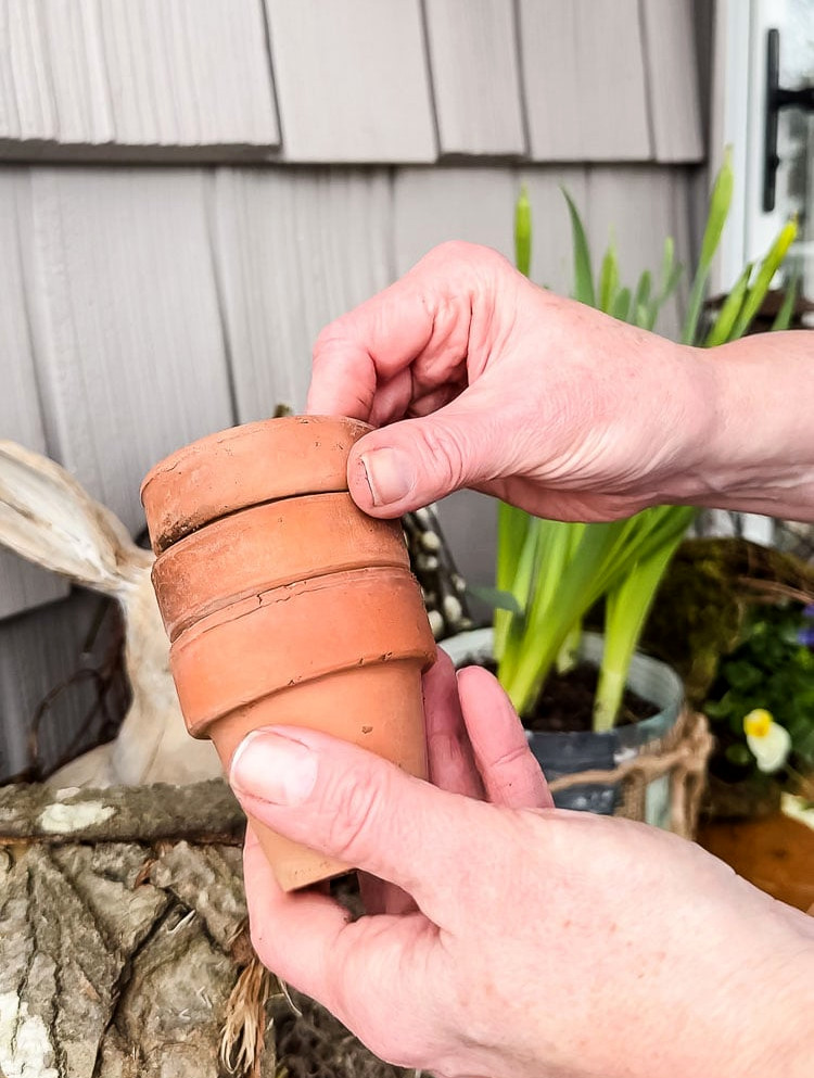 holding a stack of small terracotta pots